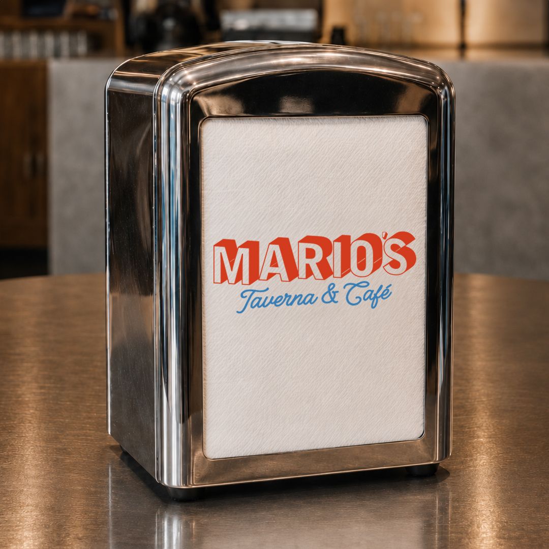 En servetthållare i krom med Mario's Taverna & Café-loggan på servetten, på en bardisk.